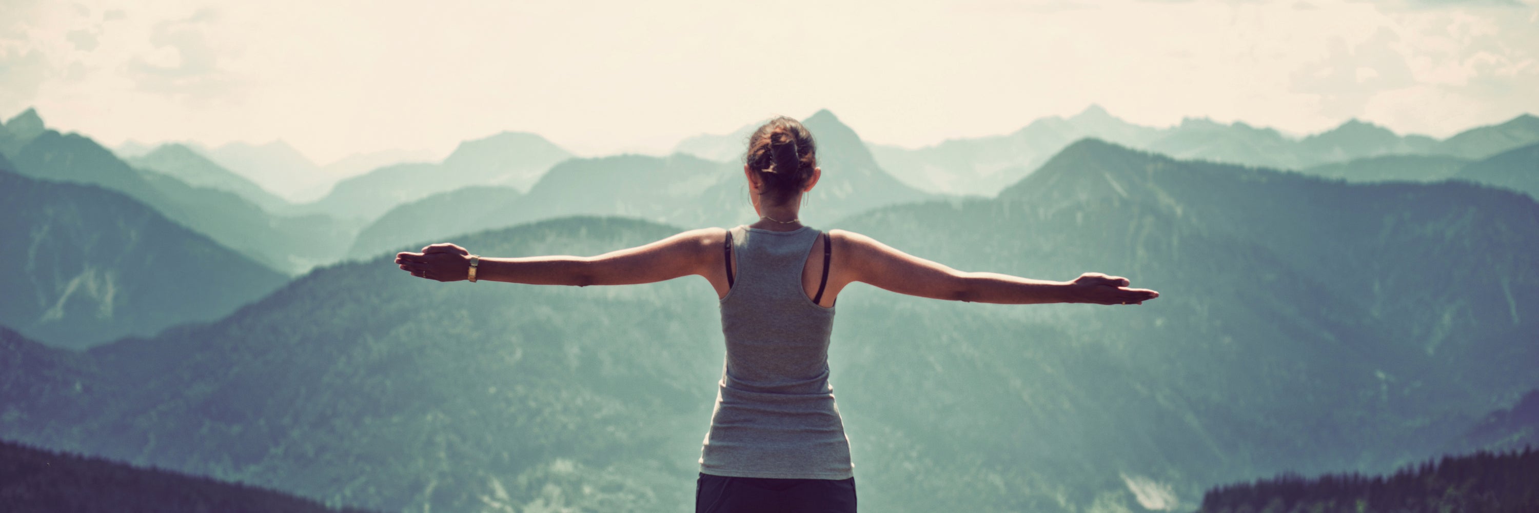 Woman standing at a viewpoint embracing the beauty. She is feeling healthy because of the holistic health products from Headley Holistics