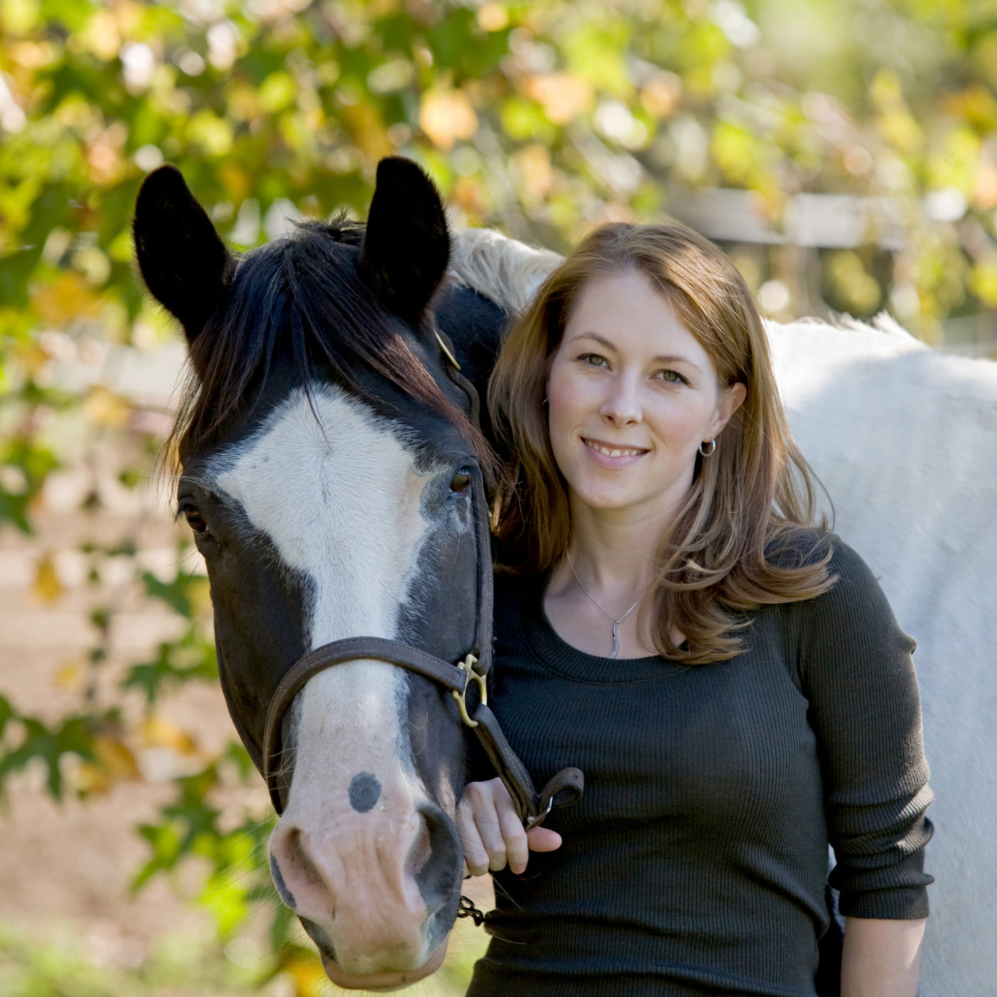 Woman happy standing with her horse, remarking how Organic Black Cumin seed Press Cake has worked very well as a natural horse fly repellent